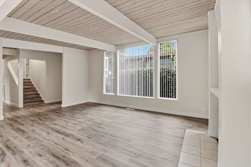 A spacious room with wooden flooring and a staircase leading to another level.