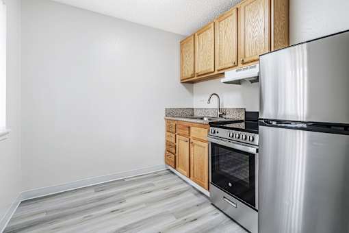 A kitchen with a stainless steel refrigerator, oven, and wooden cabinets.