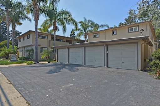 A house with a driveway and palm trees in front.