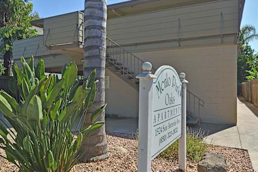 A sign for the Oaks Apartments stands in front of a building.