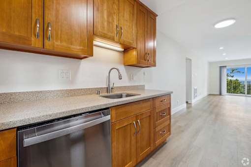 A kitchen with wooden cabinets and a stainless steel dishwasher.