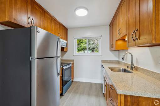 A kitchen with a black refrigerator and wooden cabinets.