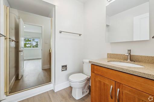 A bathroom with a toilet, sink, and mirror.