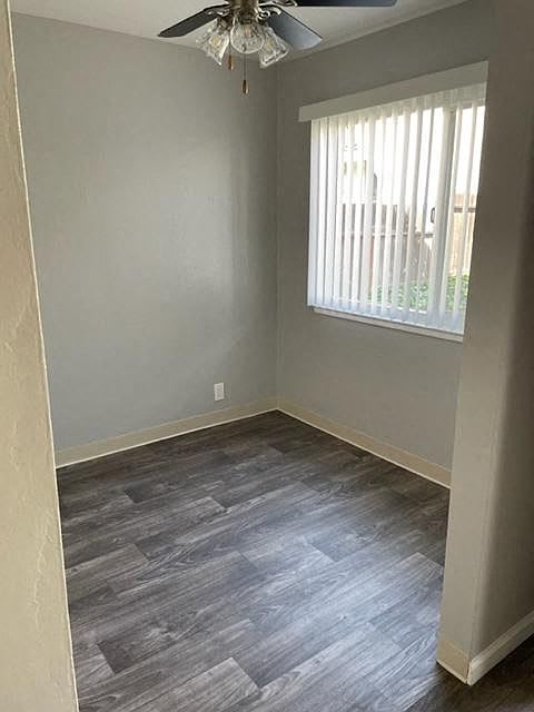 A room with a ceiling fan and a window with blinds.