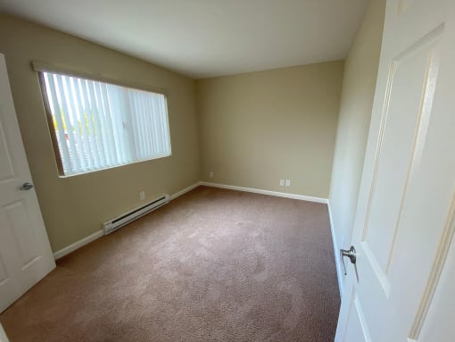 an empty room with a window and a door
