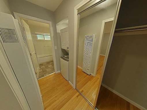 A hallway with a mirror on the wall and a washing machine in the background.