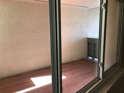 an empty room with a window and a wooden floor
