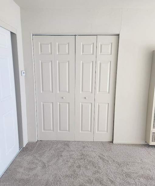 A room with a white door and a grey carpet.