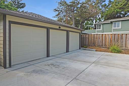 A garage with a brown roof and three white doors is shown.