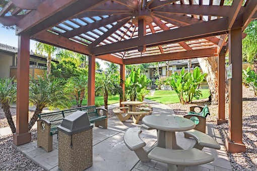 A wooden pergola with a table and chairs underneath it.
