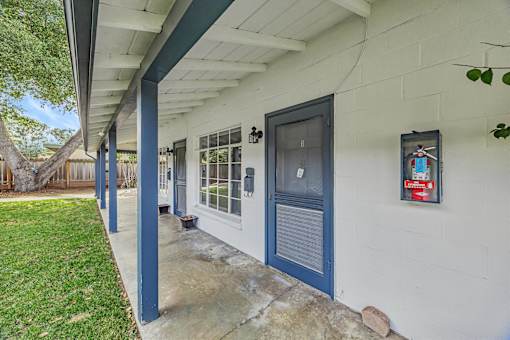 A white house with a blue door and a fire extinguisher on the wall.