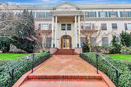 A brick pathway leads to a building with a large front door.
