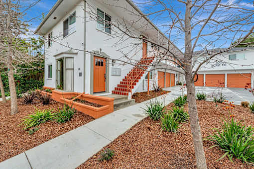 A white house with a red door and orange stairs.
