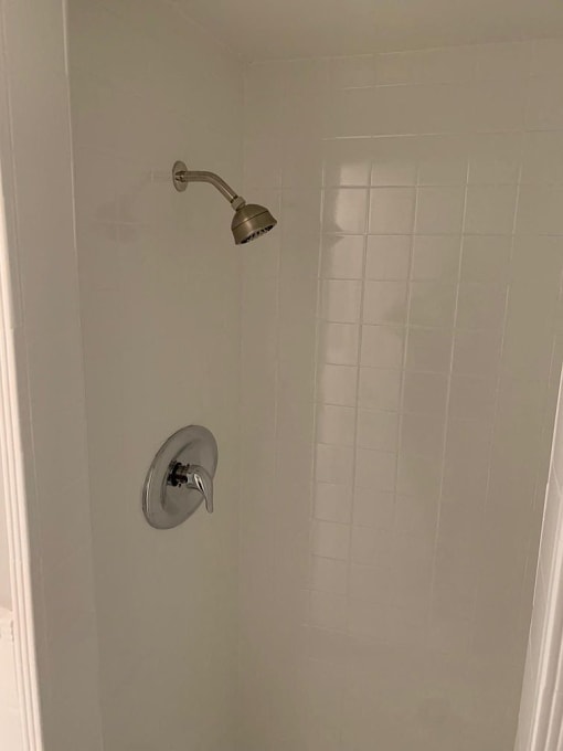 a small white shower with a silver shower head