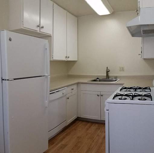 A white kitchen with a refrigerator, stove, and cabinets.
