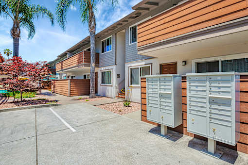 A sunny day at a residential complex with a parking lot in the foreground.