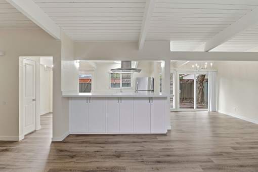A kitchen with white cabinets and a wooden floor.