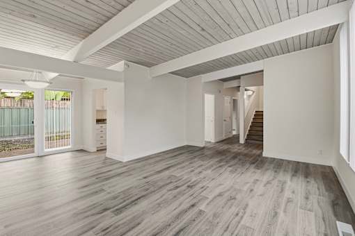 A spacious room with wooden flooring and white walls.