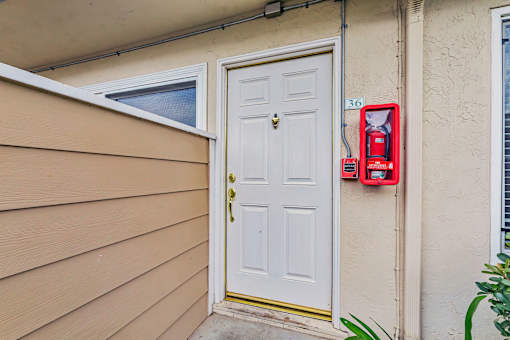 A red fire extinguisher is mounted on a wall next to a white door.