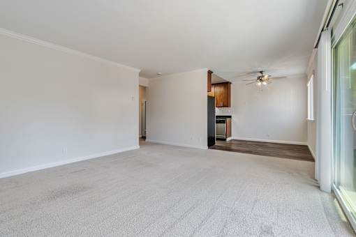 A spacious room with a ceiling fan and a door leading to another room.