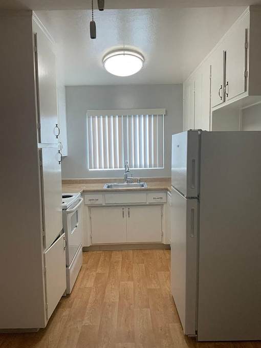 A kitchen with a white fridge and a white sink.