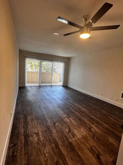 an empty living room with a ceiling fan