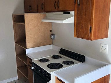 a small kitchen with a white stove and wooden cabinets