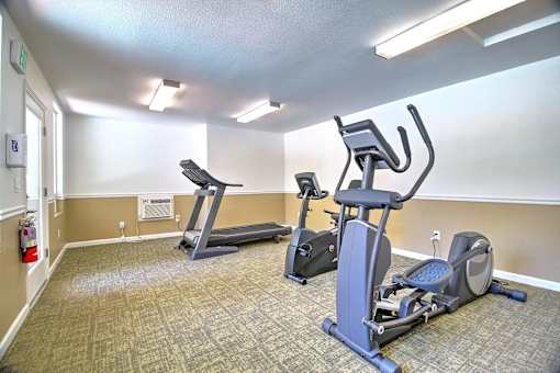 A gym room with treadmills and elliptical machines.