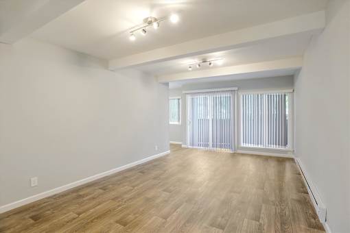A room with wooden flooring and a window with blinds.