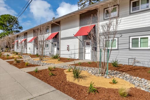 An angled view of the building with red awnings and landscaping