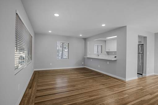 A spacious room with wooden flooring and white walls.