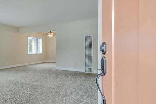 A room with a carpet floor and a window with blinds.