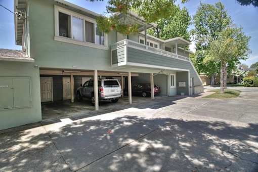 A two-story house with a car parked in the driveway.