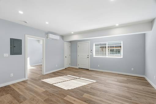 A room with wooden flooring and a window with blinds.