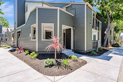 A modern house with a grey exterior and a small garden in front.