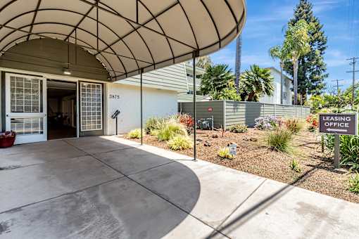 The image shows a leasing office with a curved roof and a garden in front.