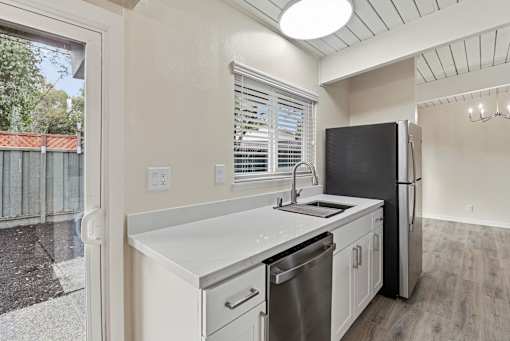 A kitchen with a black fridge and stainless steel dishwasher.