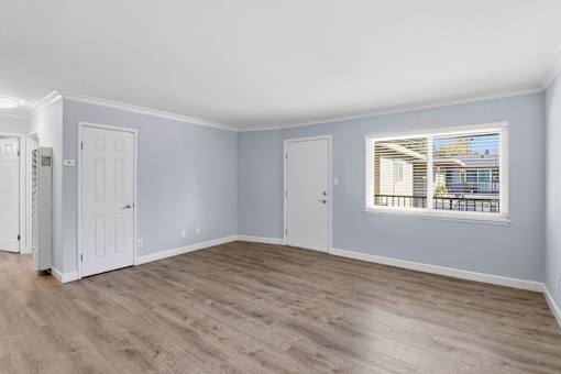 A room with light blue walls and wooden flooring with a window.