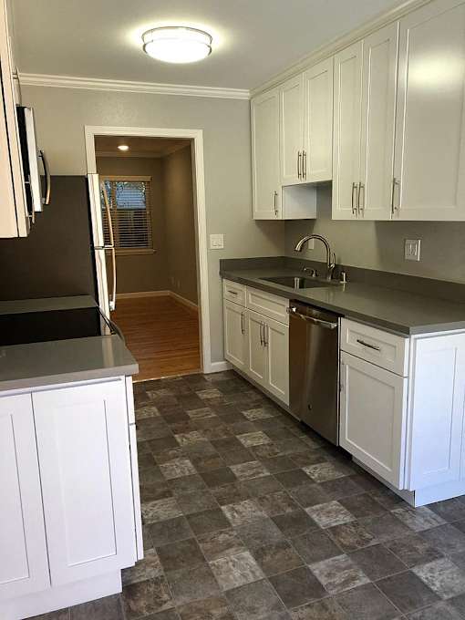 A kitchen with white cabinets and a black refrigerator.