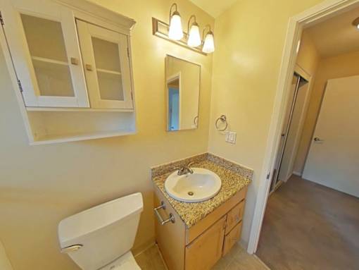 A bathroom with a sink, toilet, and mirror.
