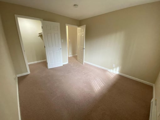 a empty room with a carpeted floor and a door to a closet