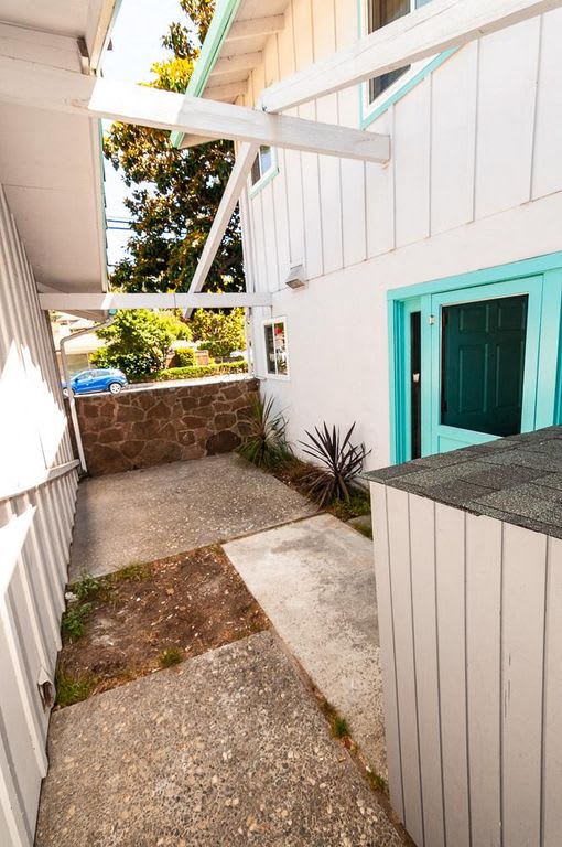 a walkway in front of a house with a green door