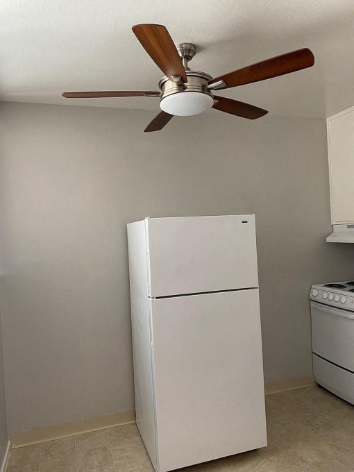 a white refrigerator in a kitchen with a ceiling fan