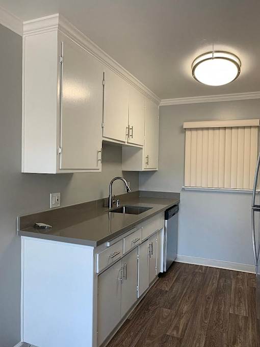 A kitchen with white cabinets and a wooden floor.