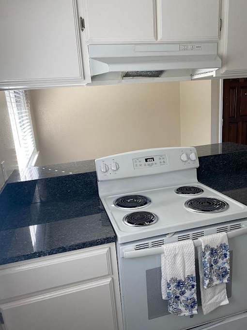 A white stove top oven with a blue and white towel hanging on it.