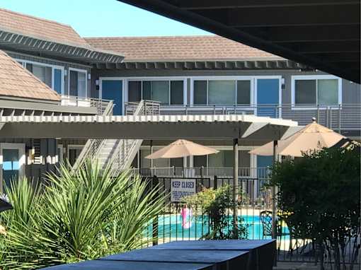 a view of a pool and a building with umbrellas