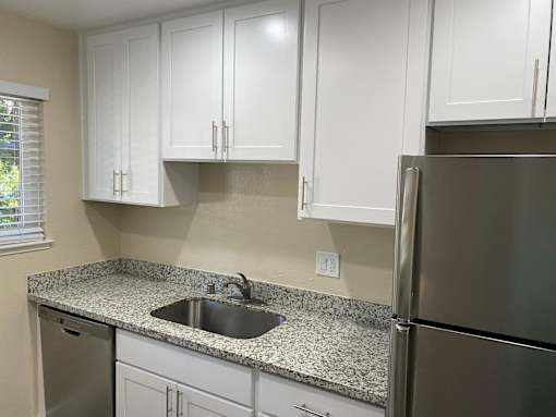 A kitchen with white cabinets and a granite countertop.