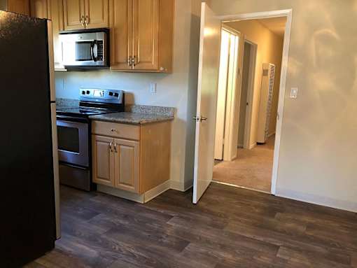 A kitchen with wooden cabinets and a black refrigerator.
