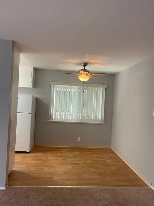 A room with a ceiling fan and a window with blinds.