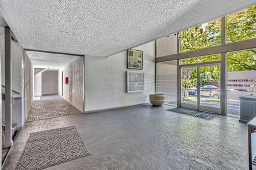 A hallway with a rug on the floor and a wall with a mirror on the side.